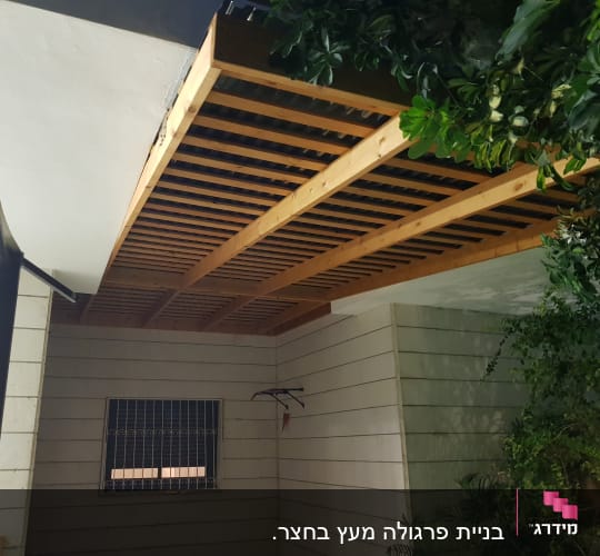 פרגולה מעץ עם צמחייה מסביב